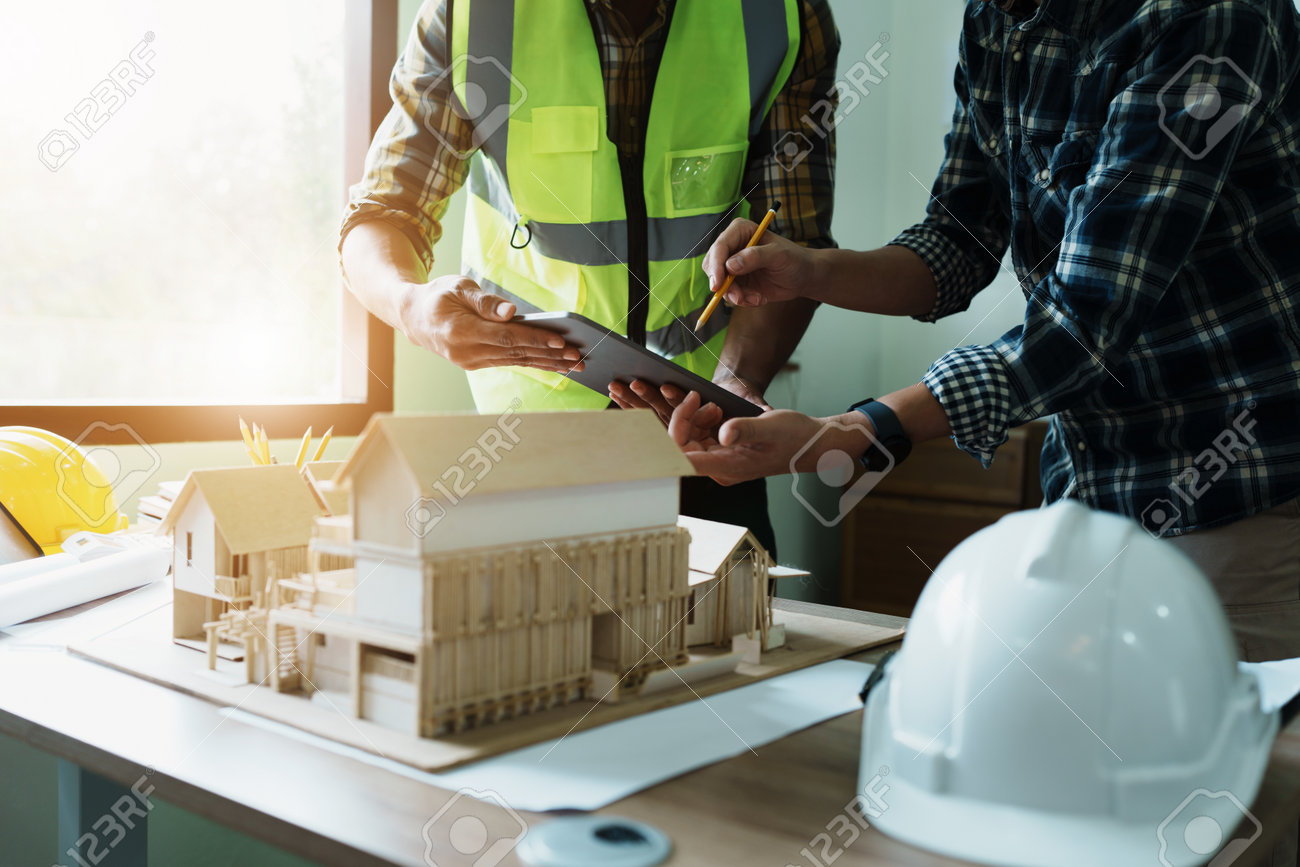 193679698-ingenieure-beraten-das-team-um-eine-architektonische-struktur-für-kunden-mit-bauplänen-und